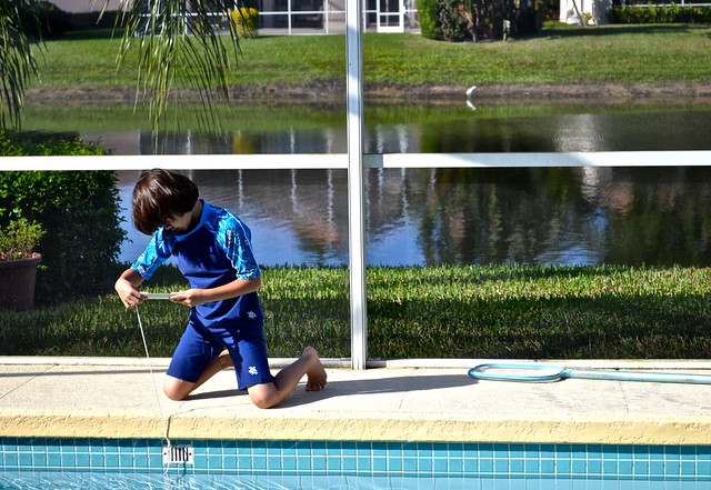 kid playing on a side of a pool while wearinga  Sun Protective Swimwear by Sungrubbies