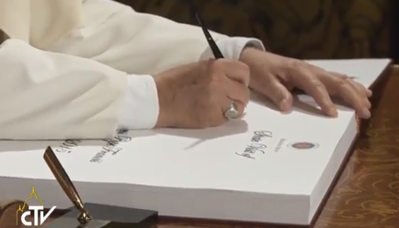 Pope Francis signs the guest book