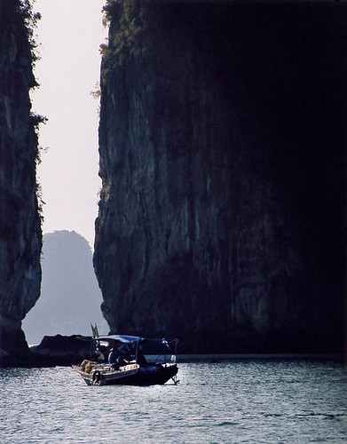 A Vietnamese Boat in the Shadow of Karst Cliffs in Halong Bay in Vietnam