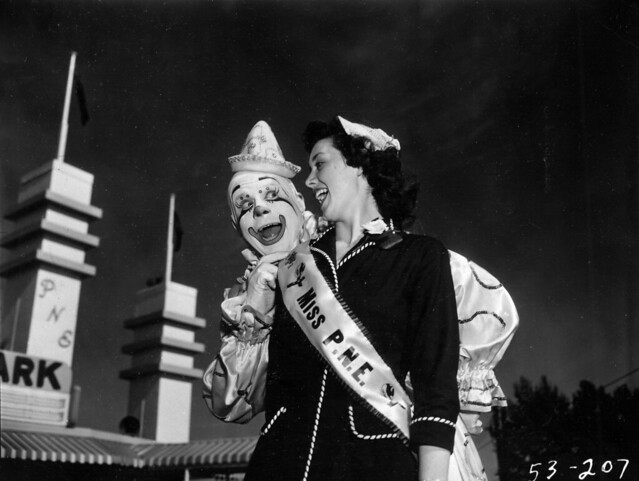 Miss P.N.E., Lynn Adcock, posing with clown at main gates to Exhibition Park