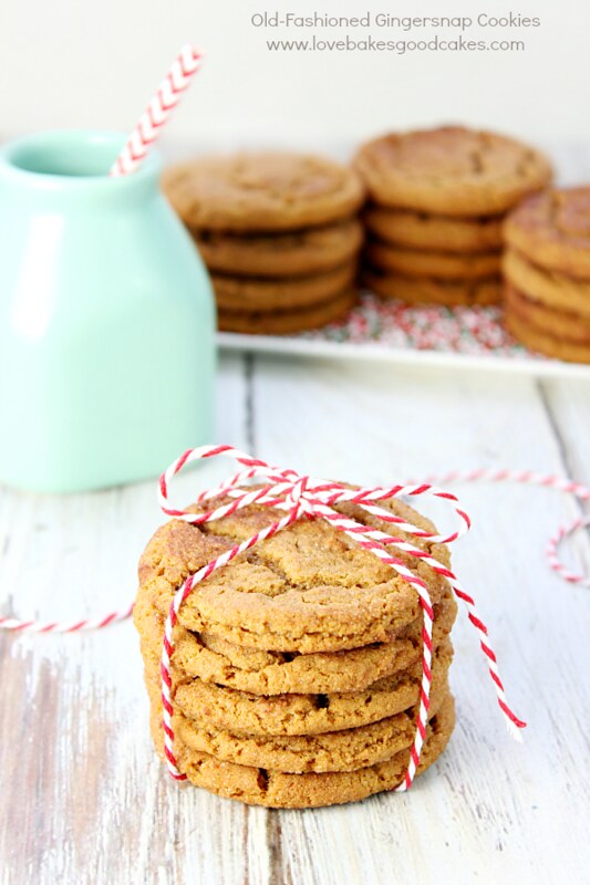 Old-Fashioned Gingersnap Cookies stacked up on a plate and stacked and tied with a glass of milk.