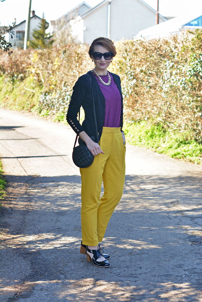 Purple t-shirt, mustard yellow trousers and black knit