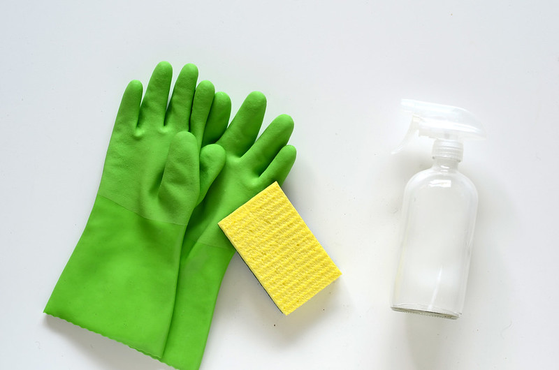 Green dishwashing gloves next to a bottle