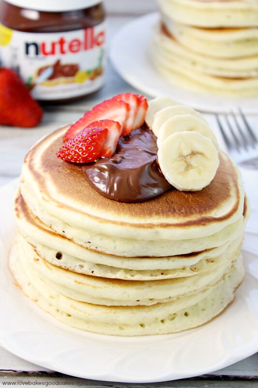 Fluffy Pancakes stacked up on a plate with Nutella and Strawberry-Banana Salsa.