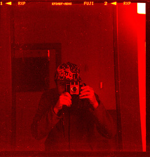 reflected self-portrait with Brownie Twin 20 camera and baseball cap