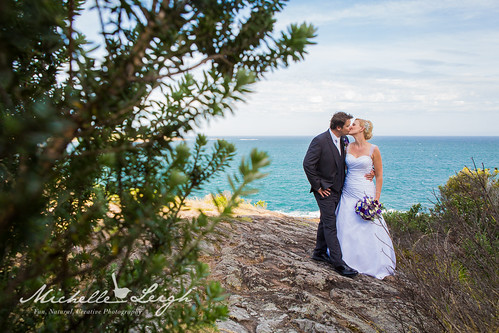 Bride and groom kissing in front of the ocean.