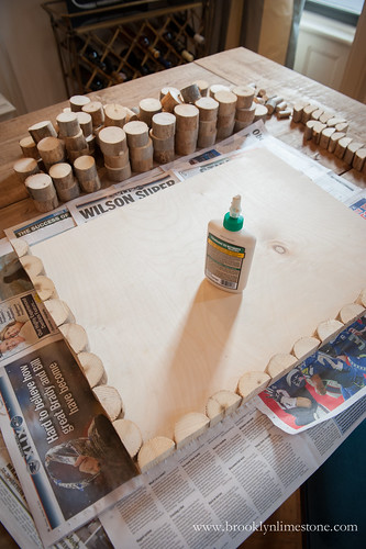 Wood Doormat with edge pieces placed on the left side and bottom with wood glue sitting in the middle of the board and wood slices for the middle sitting to the side