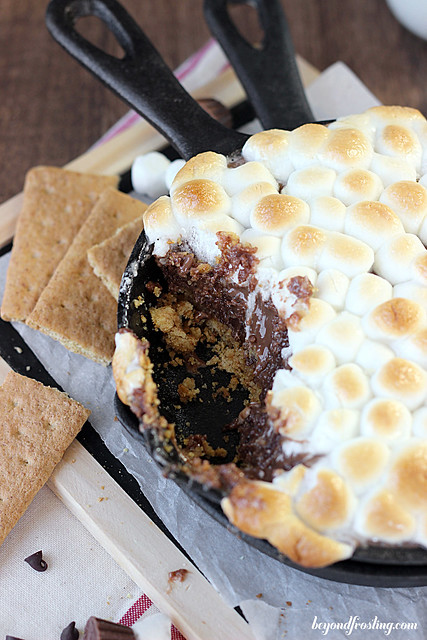 Ooey Gooey Reese's Cookie Dough S'mores Dip. The bottom layer is graham crackers, then it is topped with a peanut butter and chocolate cookie dough. This dessert dip is topped with toasted marshmallows. 