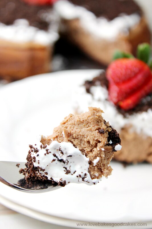Oreo Chocolate Irish Cream Cheesecake with Irish Cream Whipped Cream on a plate with a fork.