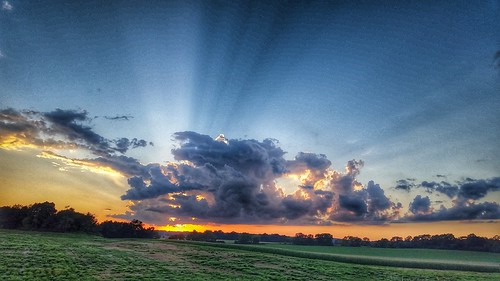 crepuscular rays sun clouds sunset field