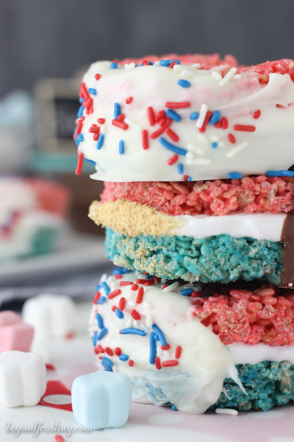Celebrate with these Patriotic Rice Krispie Treat S'mores. Red and blue Rice Krispie Treats smothered in marshmallow frosting and dipped in chocolate. Finish it off by rolling them in graham crackers. 