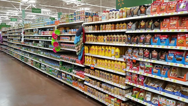 A grocery store isle with mustard products on the shelf.